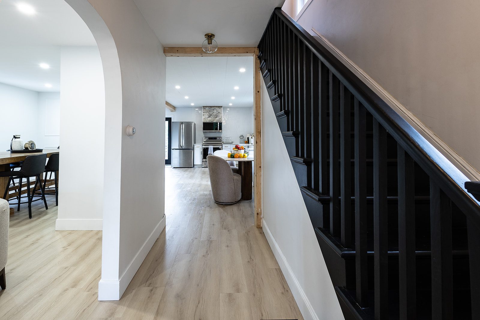 Hallway with black staircase toward kitchen