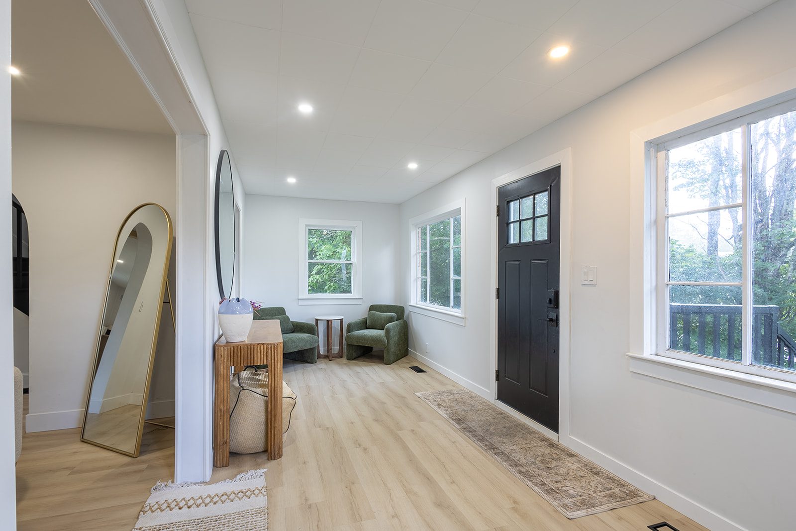 Entryway with green chairs and oval mirror